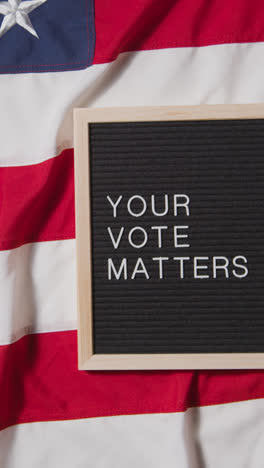 Vertical-Video-Of-Sign-Reading-Your-Vote-Matters-Lying-On-US-Stars-And-Stripes-Flag-For-American-Election-2024-3